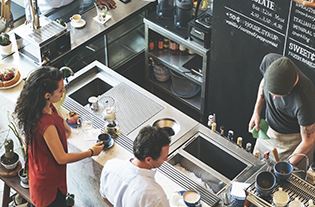 A man and a woman waiting at a counter in a coffee shop